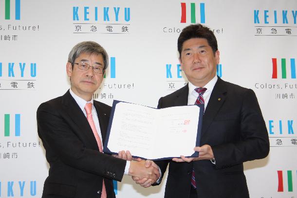 協定書を手に握手を交わす京浜急行電鉄社長と川崎市長