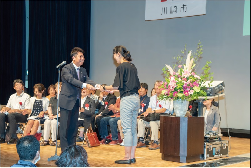 介護サービス事業所に金の認証シールを渡す市長