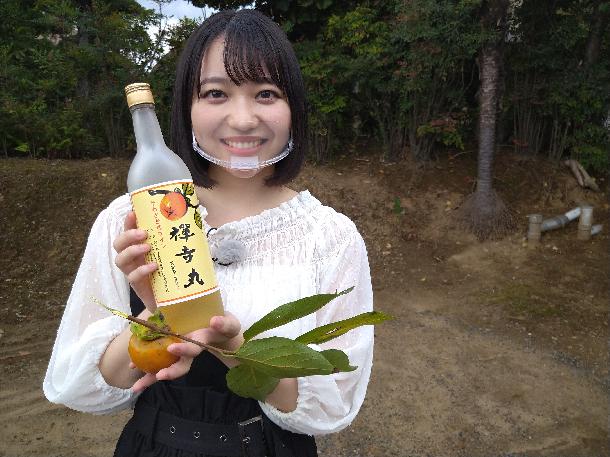 【写真】プレゼンターが禅寺丸柿とワインをもって写っています