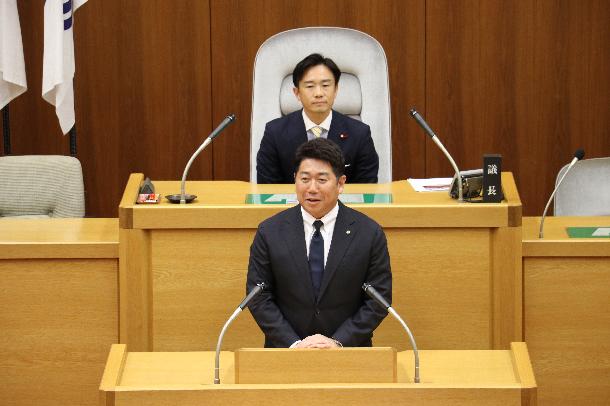 議場演壇で挨拶を述べる市長