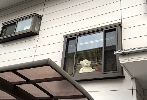 家の窓から下を見下ろしているクマさん
