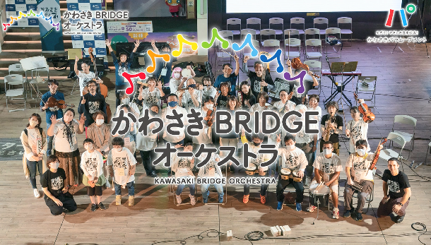 出演者の集合写真をバックにかわさきBRIDGEオーケストラのロゴが大きく表示されている画像