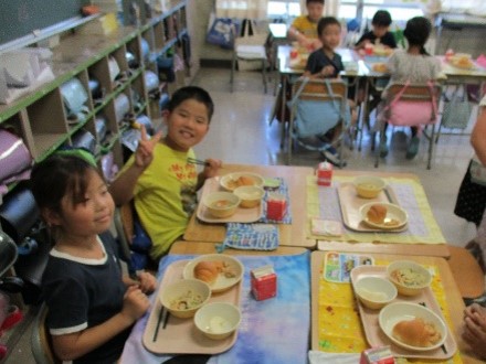 給食を笑顔で楽しむ小学生の写真