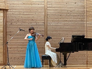 ステージで大谷康子さんがヴァイオリンを演奏し、小山さゆりさんがピアノを弾く様子