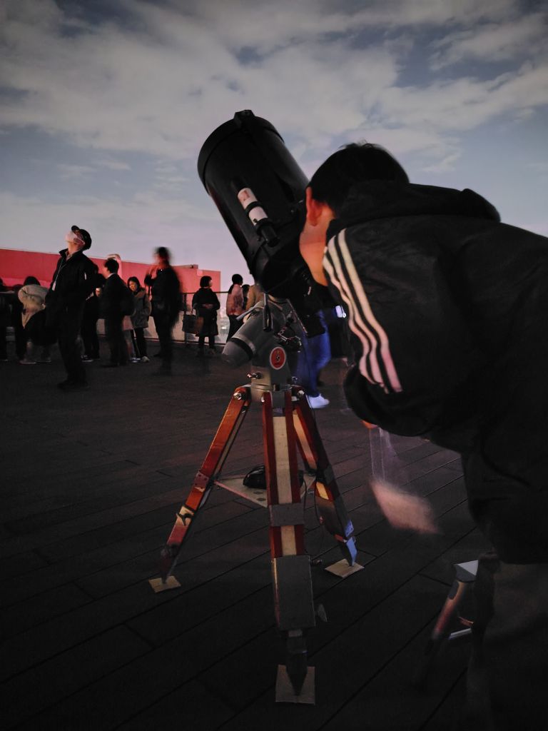 望遠鏡で雲の隙間から星を観察している参加者が写っている写真