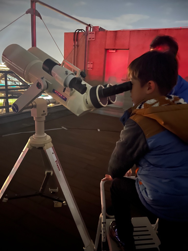 双眼鏡で雲の隙間から星空を観察している参加者が写っている写真