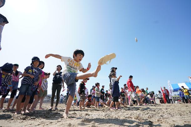 ビーチサンダルを飛ばす子供の写真