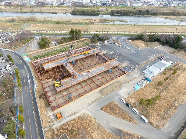 深く掘り進むにつれ、土留め（どどめ：赤く見える鉄骨）を組み上げて、土が崩れないように