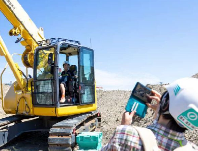 子どもがクレーン車に乗って、親が写真を撮る様子