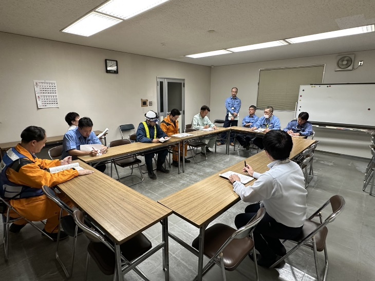 各作業班の班長が会議室に集まってミーティングしている様子