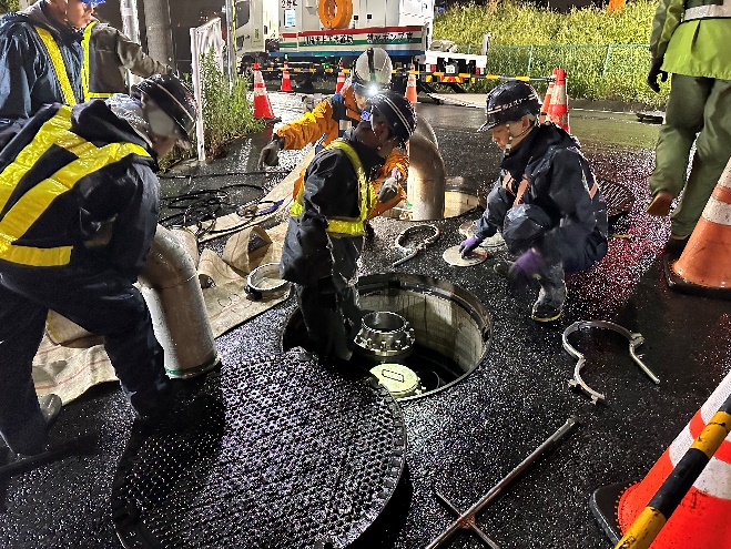 河川側に水を排水するために道路の横断管にホースをつなぐ