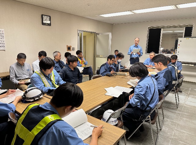 各作業班の班長が会議室に集まってミーティングしている様子