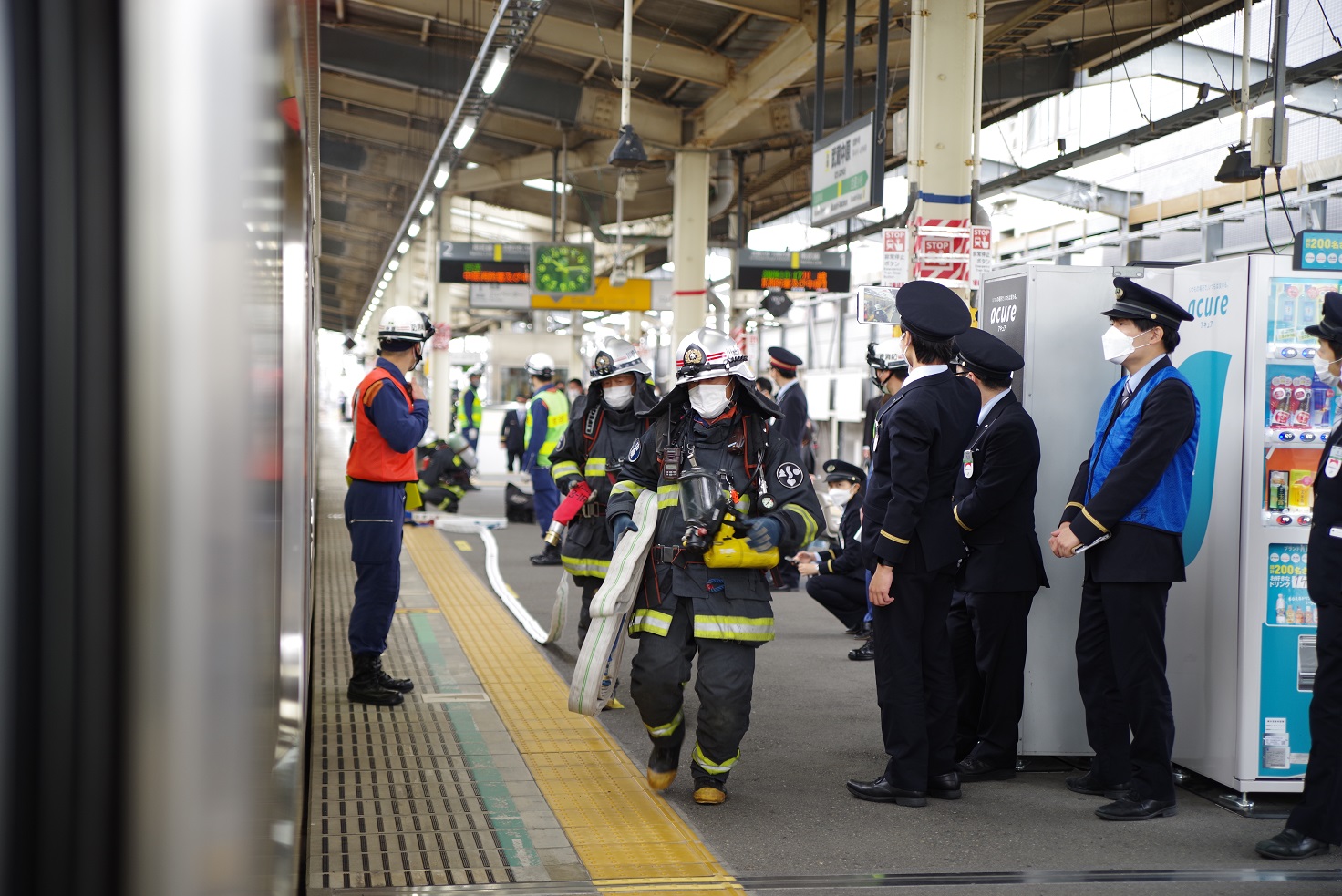 消火活動のため構内までホースを延長する消防隊写真