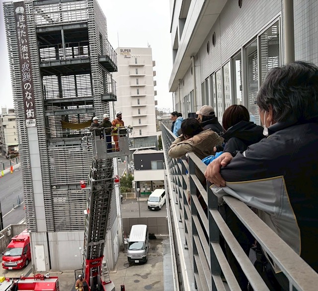 はしご車で3階まで上がるクラブ員の写真