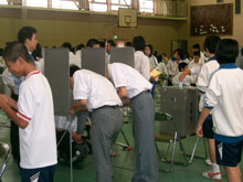 記載台で投票用紙に記載する生徒