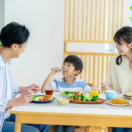 両親に囲まれて嬉しそうに食事する男児