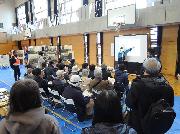 体育館で気象庁横浜地方気象台による防災講座を行っている様子。来場者が着座で講義を聴いている。